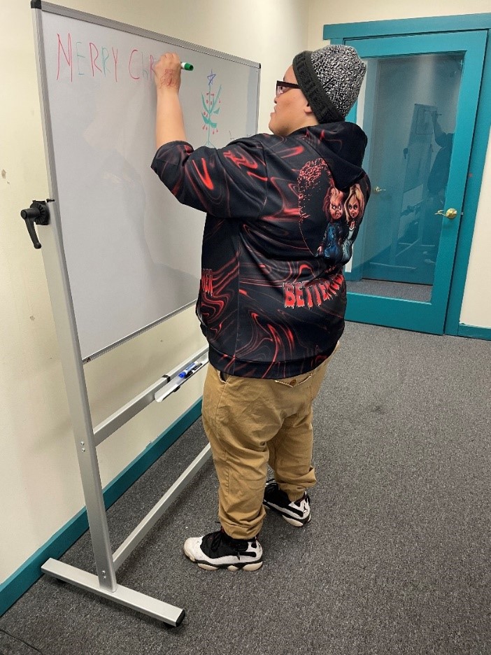 Individual in a hoodie writing on a dry erase board