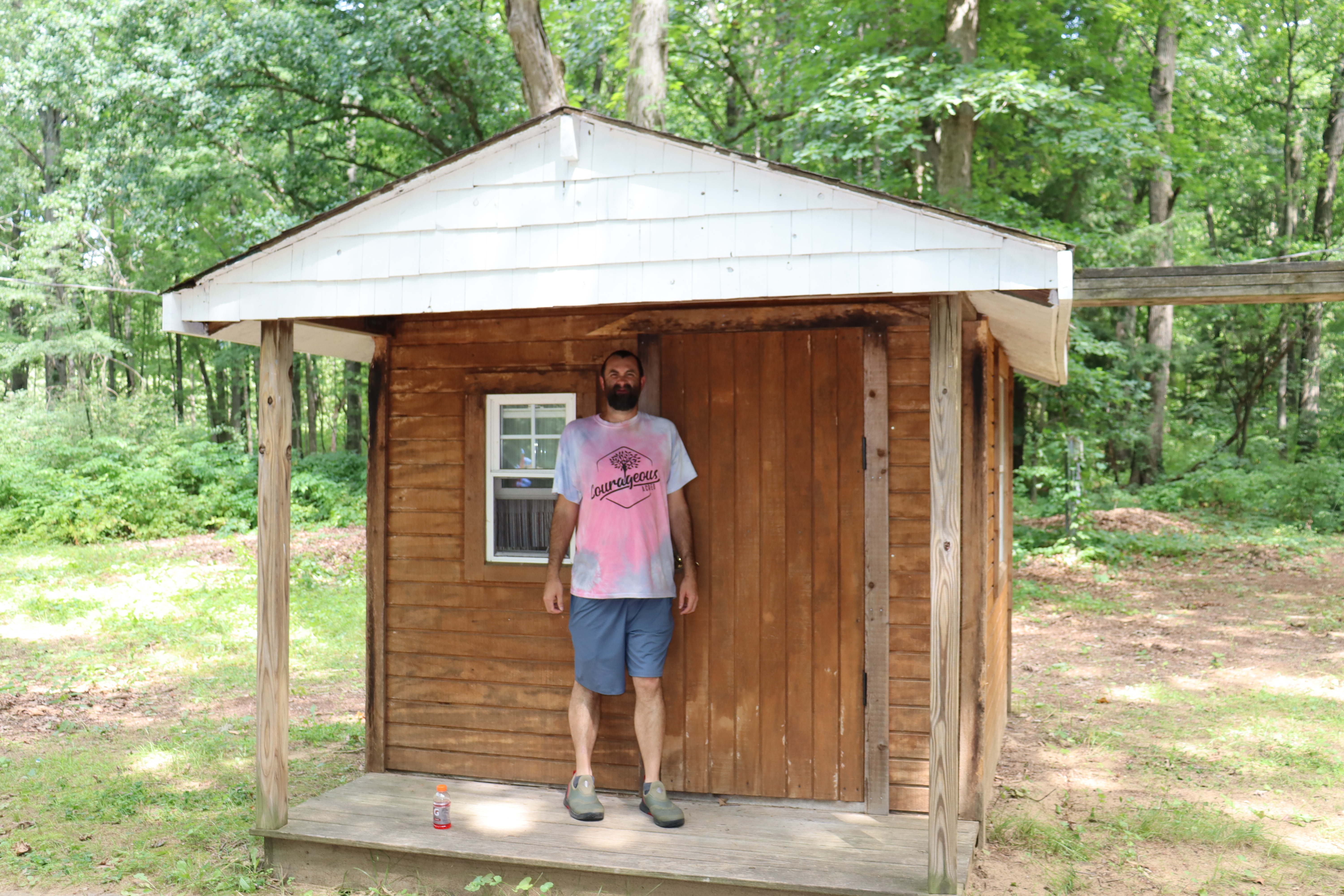 Jeremy standing in front of a wooden cabin at Courageous Acres