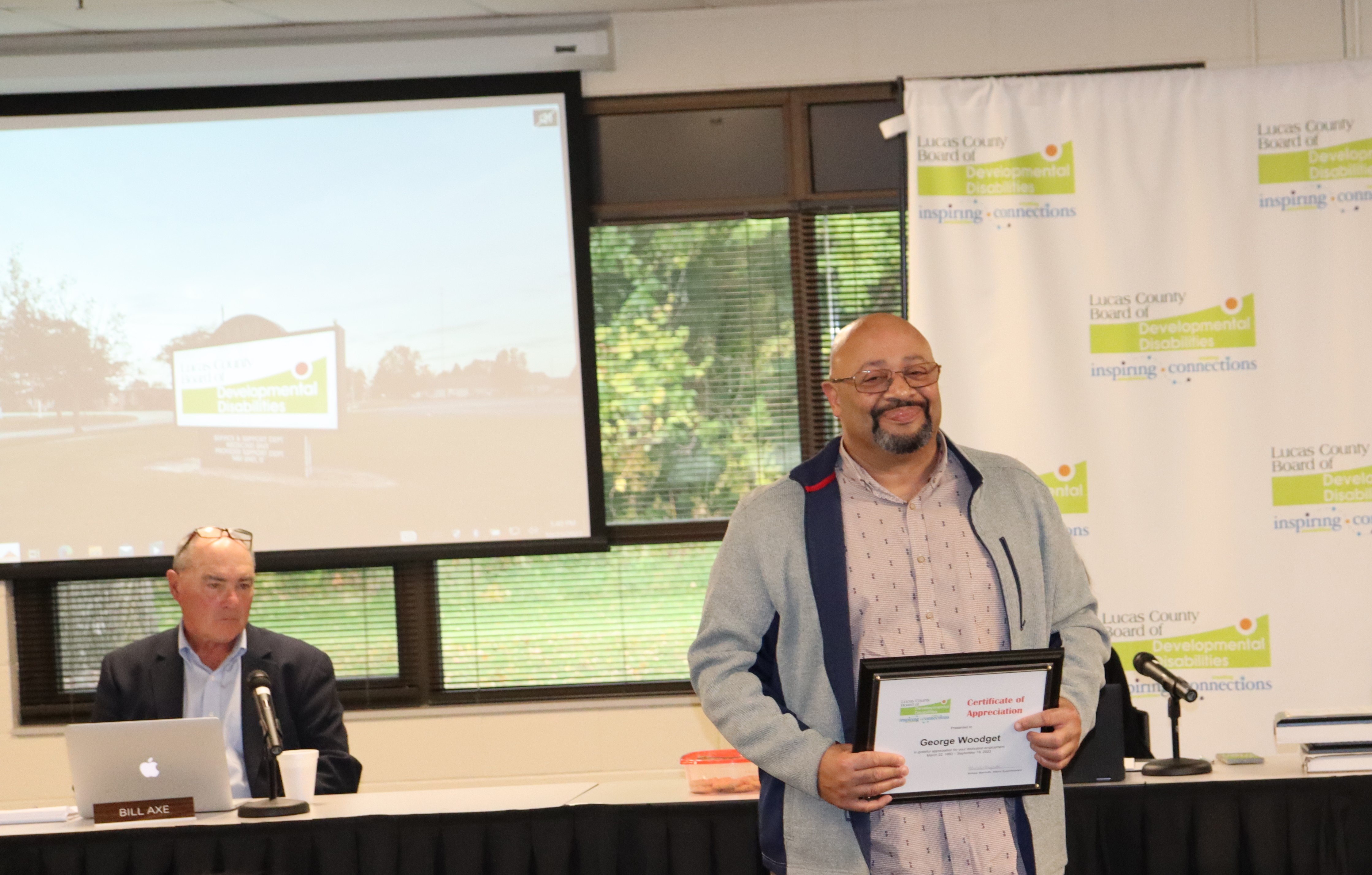 George Woodget stands with award in his hands as he addresses the Board in recognition of his retirement