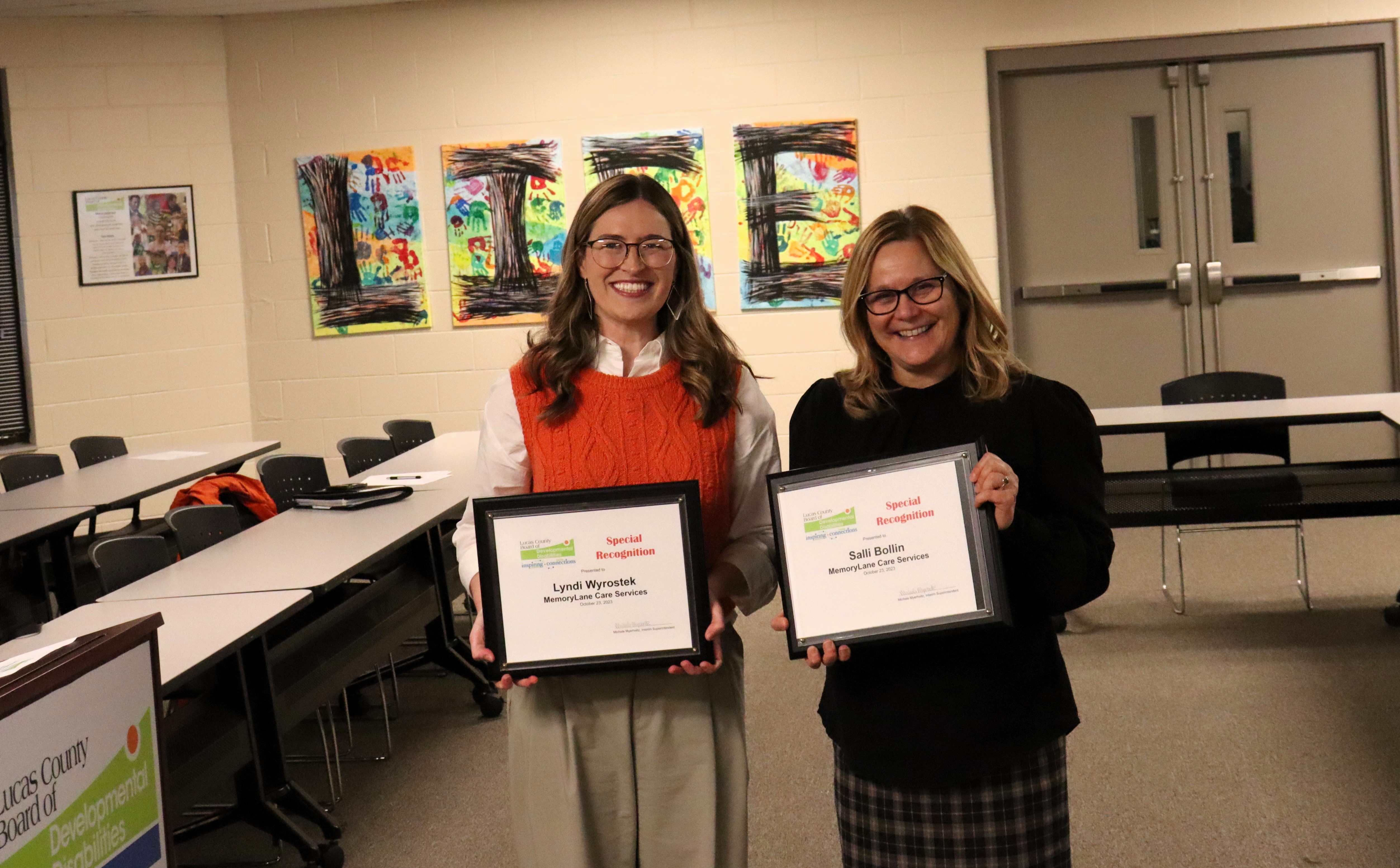 Two women holding awards after being recognized by the Board of DD