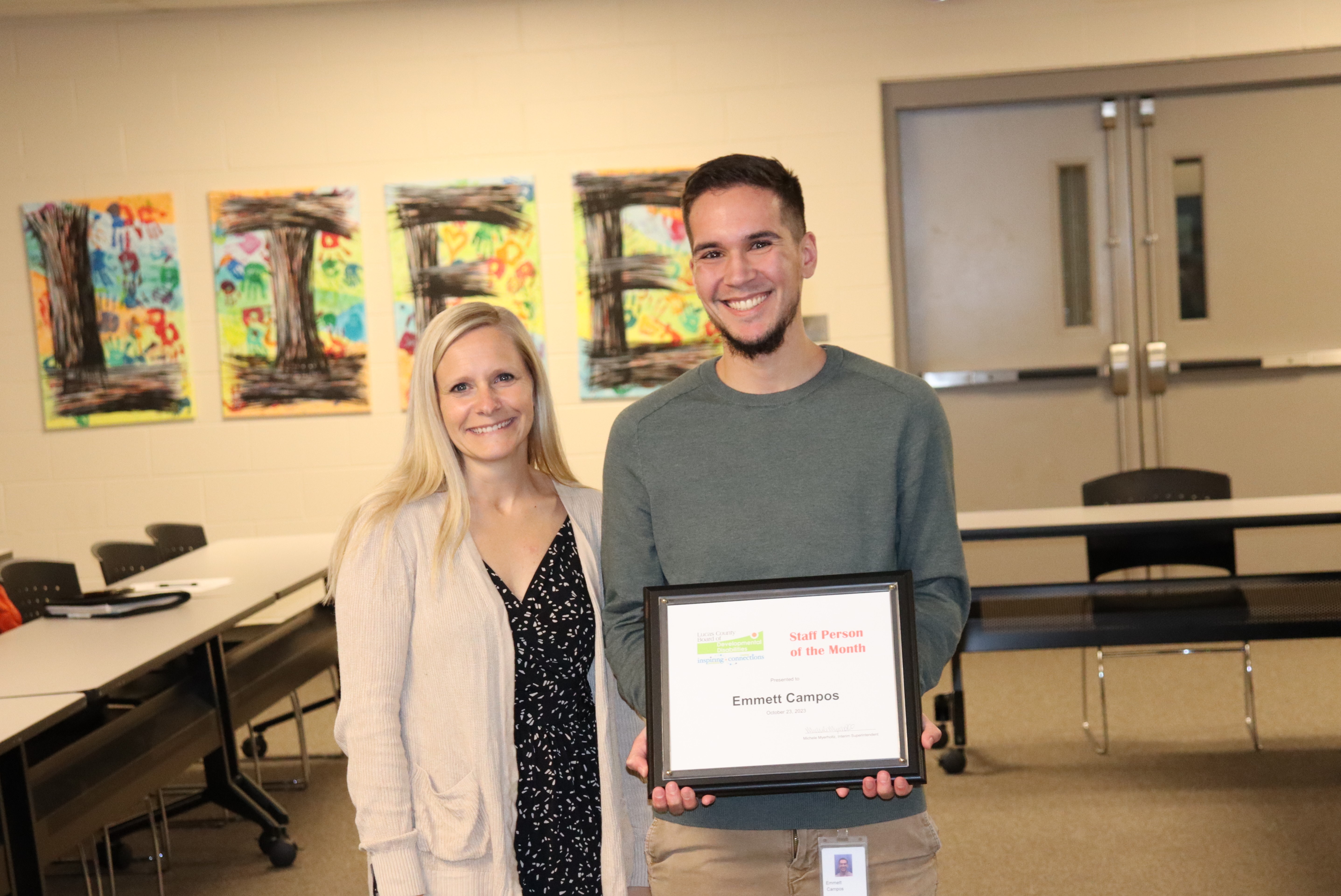 Young man holding award certificate with his department director standing next to him. 