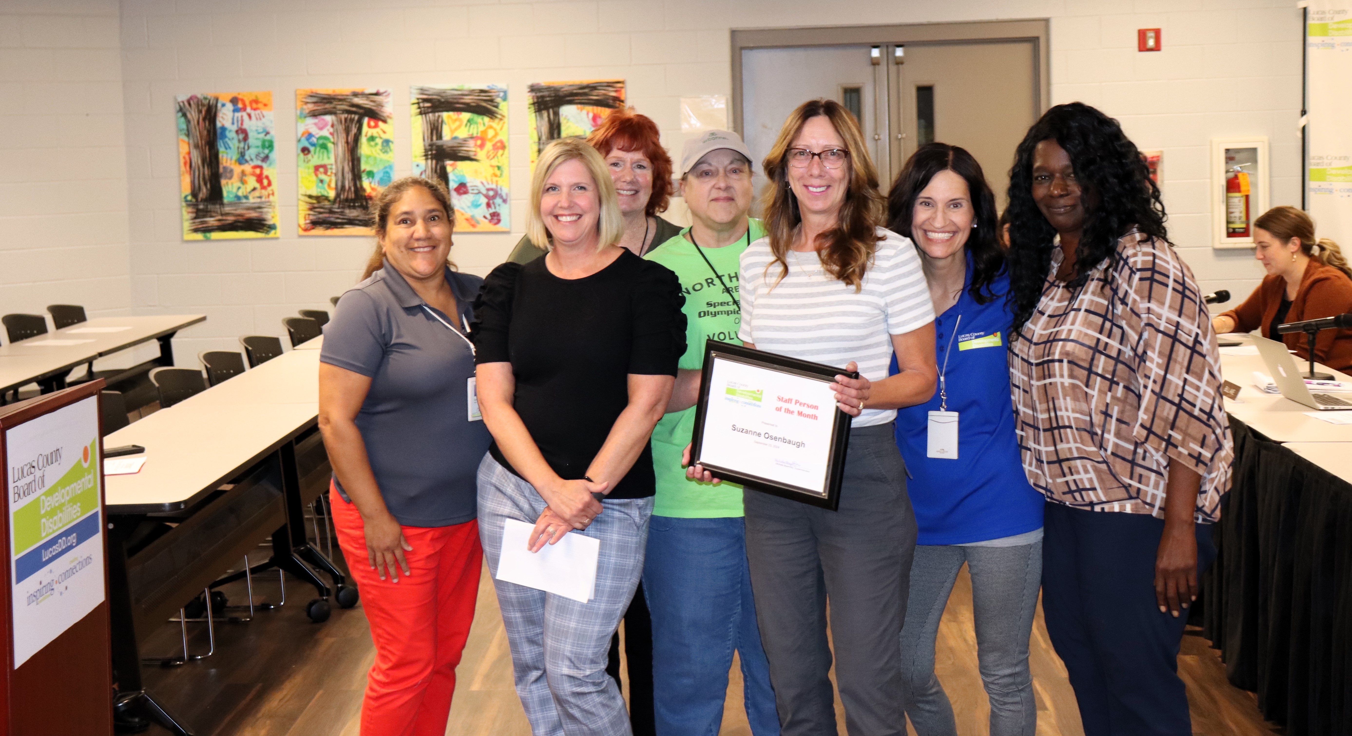 Lucas DD Staff Person of the Month Sue Osenbaugh, center, surrounded by 6 of her colleagues as she receives her award