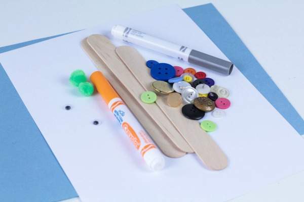 Supplies for crafting - markers, buttons and popsicle sticks - on top of paper