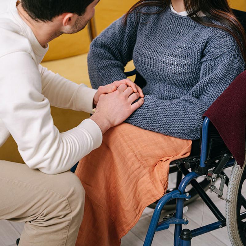Man Holding Hand of Individual Using a Wheelchair