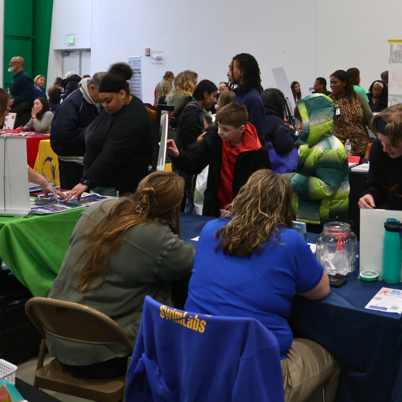 People seated at the inclusion fair speaking with people standing